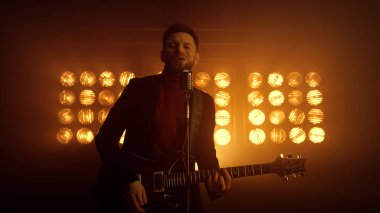 Müzisyen adam sahne gece kulübünde solo performans sergiliyor. Gitar çalan vokalist.