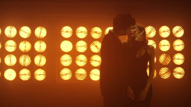 Gece kulübünde birbirine sarılan iki sevgili. Spot ışıklarında dans eden seksi çift