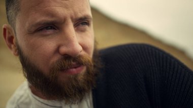 Düşünceli bir adamın yüzü doğaya bakmıyor. Yakışıklı sakallı adam..