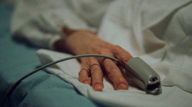 Hasta hasta oksijen maskesi hastanede dinleniyor. Nabız oksimetresi parmağa yakın çekim.