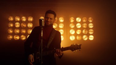 Müzisyen adam içeride elektro gitarda solo çalıyor. Gitarist müzik çalıyor.