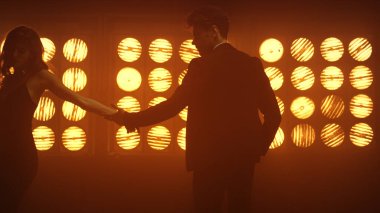 Kulüp lambalarının yanında el ele dans edin. Kadın avucuna dokunan adam uzaklaşıyor.