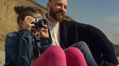 Küçük çocuk aile plaj gezisinde fotoğraf çekiyor. Tatlı kız, kamerayı dışarıda tut..
