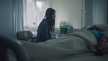 Kadın, hasta adamı hastane koğuşunda teselli ediyor. Modern klinik ameliyathane.