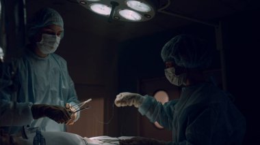 Profesyonel tıp çalışanları karanlık ameliyathanede ameliyat yapıyor..