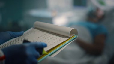 Hemşire elleri hastane bulaşıcı ünitesinde pano tutarken not alıyor..