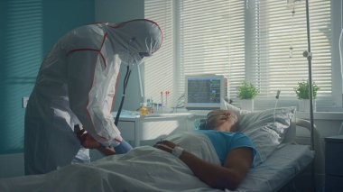 Steteskopla hastanın nabzını dinleyen doktorlar. Hasta adam baygın yatıyor..