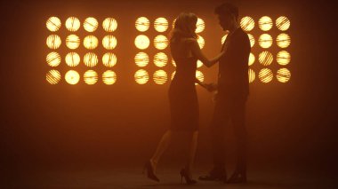 Gece kulübünün ışıklarında seksi dans eden şehvetli çift. Kadın, iten adamla flört ediyor..