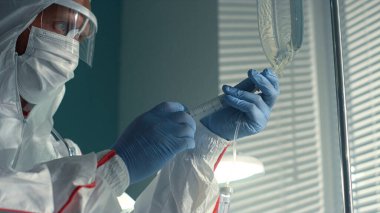 Doktor hastane bulaşıcı hastalıklar biriminde serum torbası kullanarak tıbbi şırınga çekti..