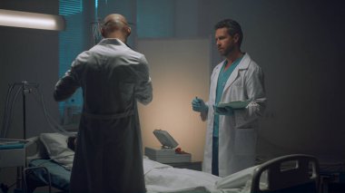 Hastane koğuşunda danışmanlık yapan iki doktor. Hastayı muayene eden sağlık görevlileri.