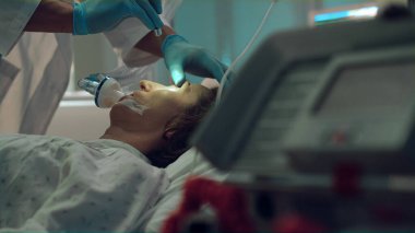 Doktor yoğun bakımda fener testiyle hasta oksijen maskesini kontrol ediyor..