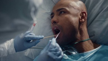 Sağlık çalışanı koğuşta ölüm sebebini test ediyor. Hasta hasta hastane yatağında yatıyor.