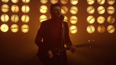 Sahnede gitar çalan bir adam. Adam kulüpte şarkı söylüyor..