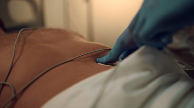 Doktor hastanın göğsüne EKG kablosu bağladı. Hastanenin kalp tedavisi.