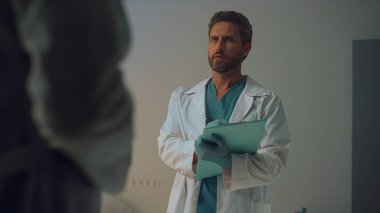 Hastane koğuşunda doktor randevusu. Ciddi terapist not defterine not alıyor..