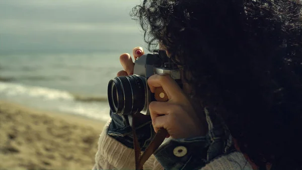 Piękna pani robi zdjęcia na plaży morskiej. Etniczka używająca klasycznej kamery. — Zdjęcie stockowe