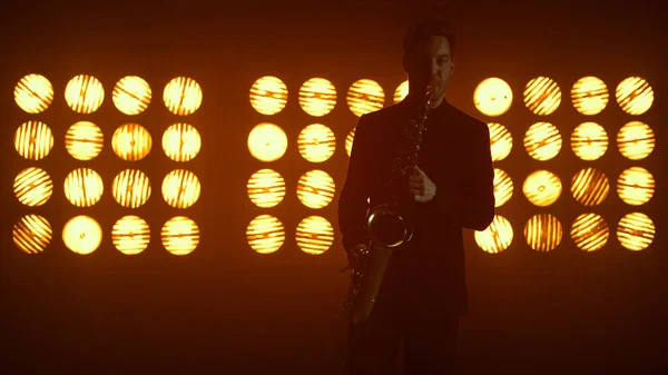 Yetenekli saksafoncu sahnede enstrüman çalıyor. Adam saksafon çalıyor.