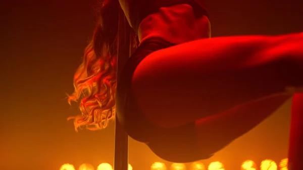 Fit woman dancing erotic moves in strip club. Closeup body performing poledance — стоковое фото
