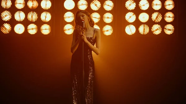 Cantante rubia interpretando sensual canción en focos. Mujer joven cantando solo. —  Fotos de Stock