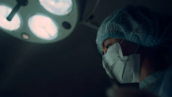 Portret pielęgniarki wykonującej operację trzymając zacisk medyczny na sali operacyjnej. — Zdjęcie stockowe