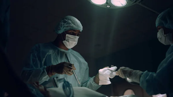 Серьезный хирург, проводящий хирургическое лечение в палате. Сотрудничество медицинской команды. — стоковое фото