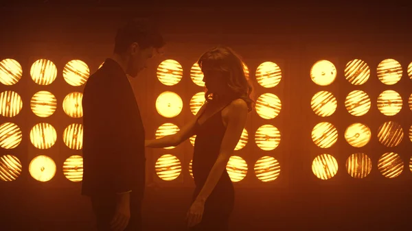 Sahne ışıkları altında şehvetli danslar yapan bir çift. Bir kadın, bir erkekle tutkuyla hareket ediyor.