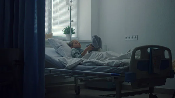 一人で病院のベッドに寝そべってる。動揺した子供プレイソフトおもちゃでクリニックルーム. — ストック写真