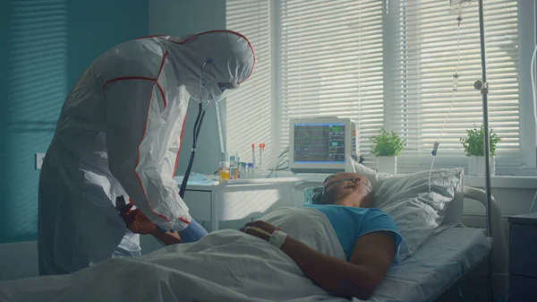 Steteskopla hastanın nabzını dinleyen doktorlar. Hasta adam baygın yatıyor..