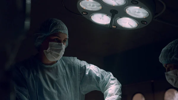 Una cirujana operando en el hospital. Cooperación de los trabajadores médicos — Foto de Stock
