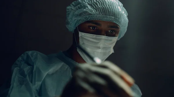 Cirujano confiado operando paciente en hospital oscuro retrato sala de emergencias. —  Fotos de Stock