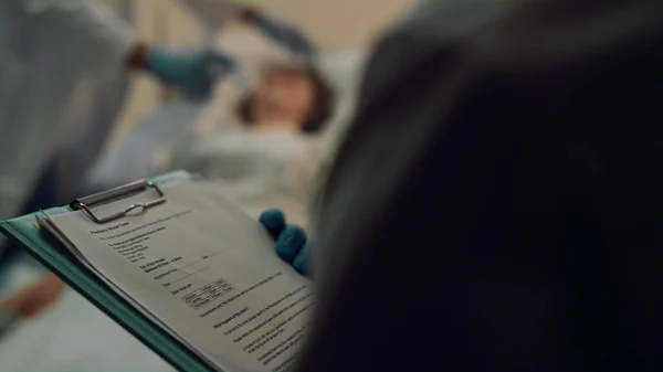 Médico segurando prancheta médica tomar nota close-up. Unidade de terapia intensiva hospitalar — Fotografia de Stock