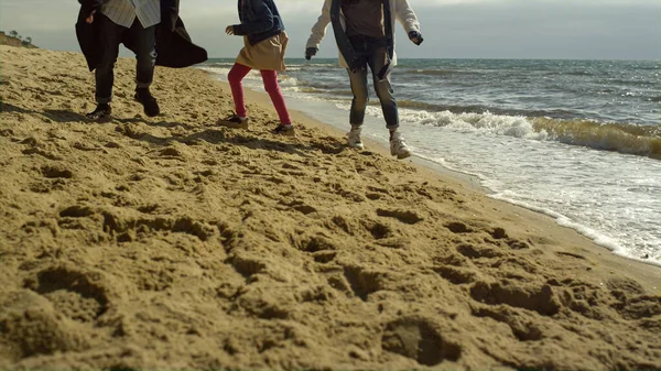 Rodzinne nogi bawią się na plaży nad brzegiem morza. Zabawa ludzi spacerujących przez fale oceanu. — Zdjęcie stockowe