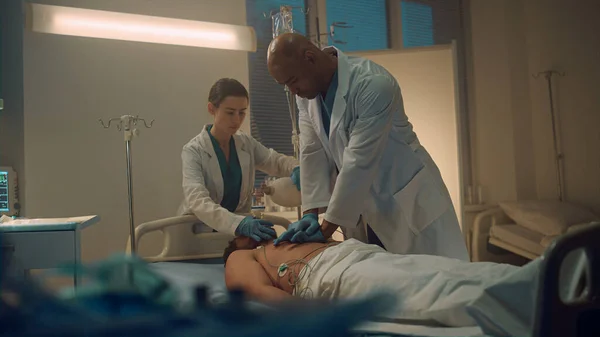 Doctor performing cpr in emergency unit room. Nurse assisting with oxygen mask. — ストック写真