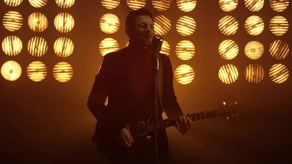 Sahnede gitar çalan bir adam. Adam kulüpte şarkı söylüyor..