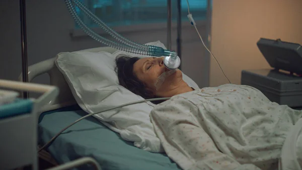 Oxygen mask patient lying in empty hospital ward. Medical tools table close up. — ストック写真