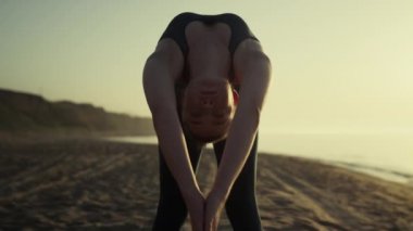 Kumlu sahilde yoga yapan seksi kız tepelere ve mavi gökyüzüne karşı..