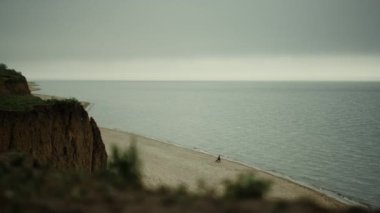 Scenic view coastline with sandy hill gloomy day. Grey cloudy sky over ocean. 