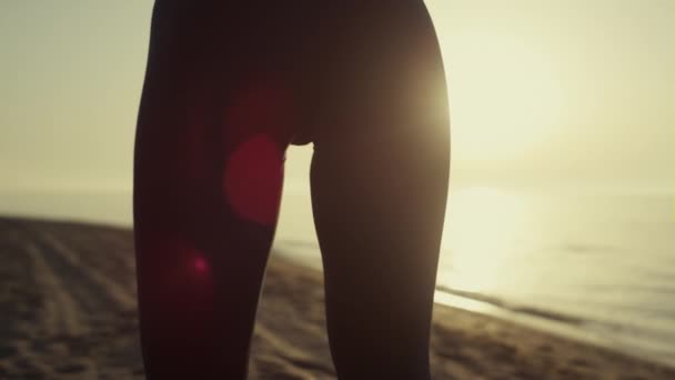 Mulher silhueta esticando a luz do sol. Menina atlética praticando ioga na praia. — Vídeo de Stock