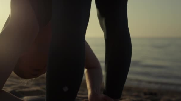 Atleta menina inclinando a cabeça aos pés fazendo exercícios de alongamento na praia de perto. — Vídeo de Stock