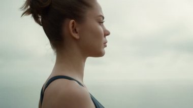 Spor kızı kameraya dönüp plajda yoga egzersizi yapıyor. Yakından..