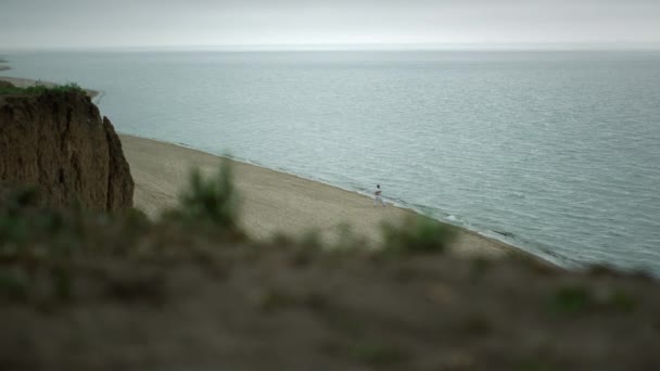 Pittoresk uitzicht wild strand met onbekende man training vechtsport bewolkt dag. — Stockvideo