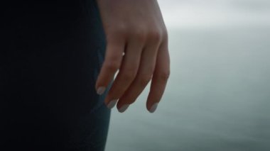 Tepedeki deniz sahilinde dikilen yakın el kızı. Kadın sakin okyanusun tadını çıkarıyor..