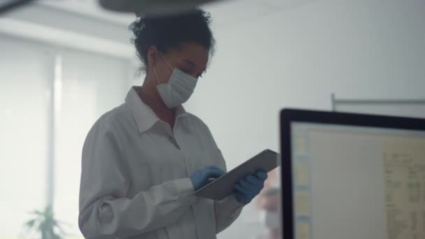 Doctor woman checking analysis results on tablet standing clinic office close up — Stock video