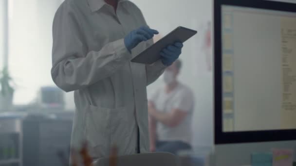 Trabajador de medicina escribiendo la información del paciente en la tableta de pie oficina moderna. — Vídeos de Stock