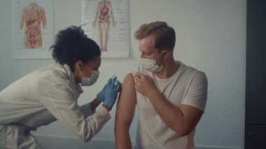 Klinikte kovid19 aşısı olan bir adam. Hemşire iğne yapıyor.