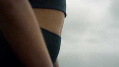 Spor giyim sektöründe sıska bir kadın var. Sahilde ayakta duran atletik bayan.