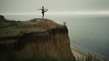 Tepede yoga yapan sağlıklı bir kadın. Kumsalda jimnastik yapan kız.