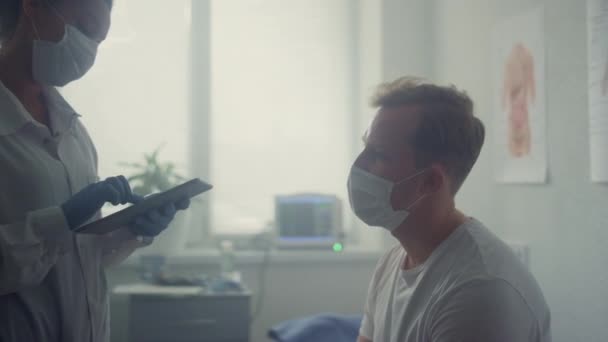 Muž pacient poslech lékař radí sedí v moderní nemocniční kanceláři zblízka. — Stock video