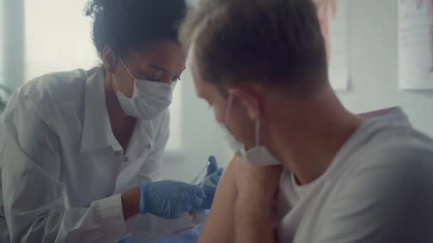 Ofis kliniğinde ikna edici aşı yaptıran adam. Doktor iğne yapıyor. — Stok video