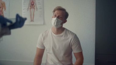 Young guy patient consulting with medical specialist sitting clinic close up. 